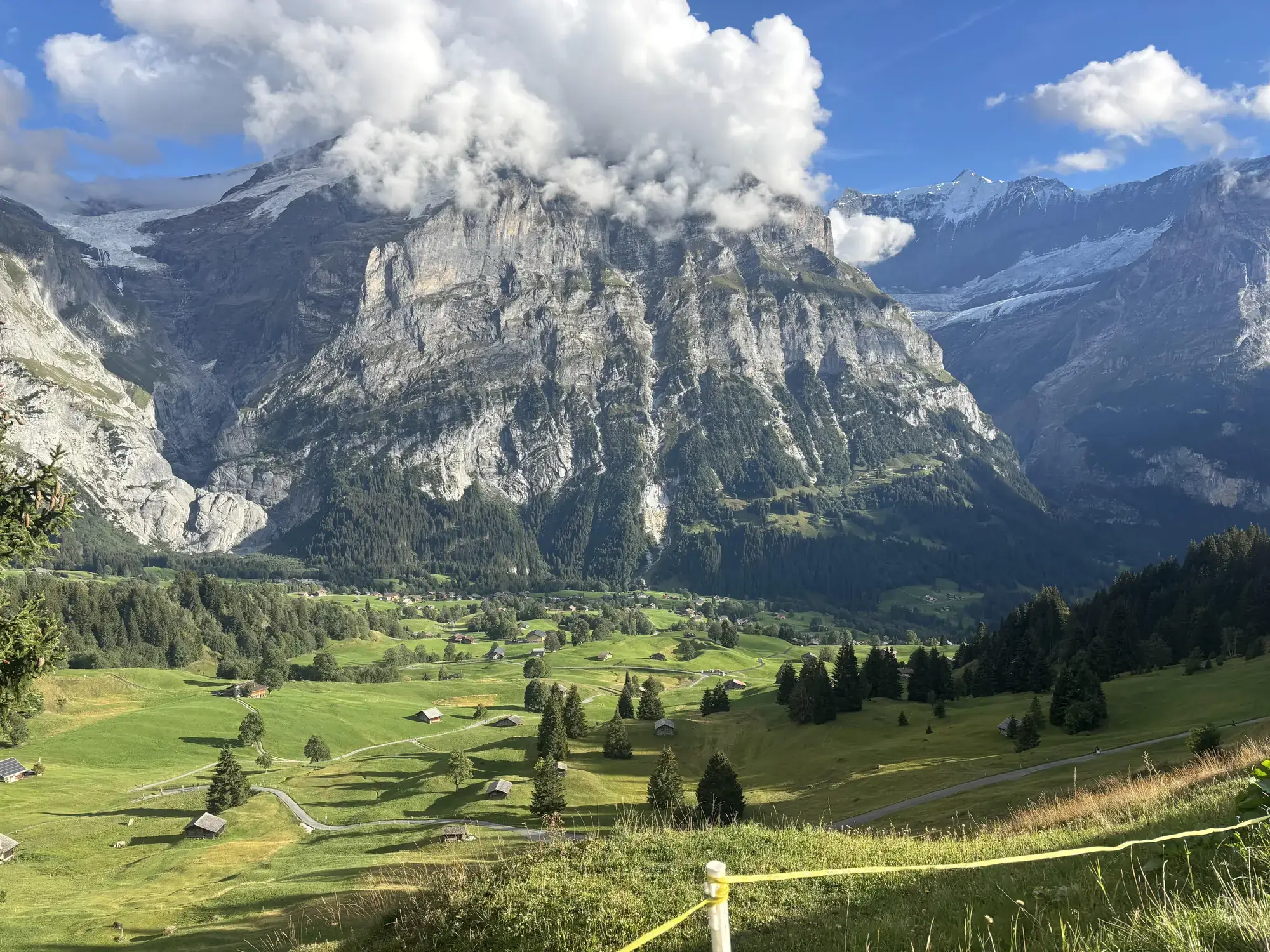 Green alpine meadows and chalets beneath cloud-capped peaks in Grindelwald, Switzerland