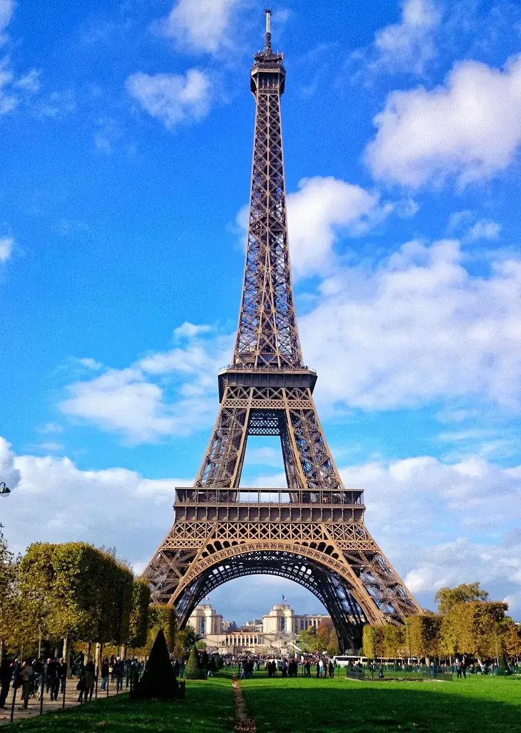 The Eiffel Tower rising over the Champ de Mars under a blue sky